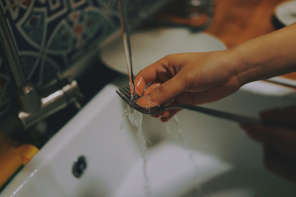 Washing a fork in the sink. Chores help kids learn responsibility.